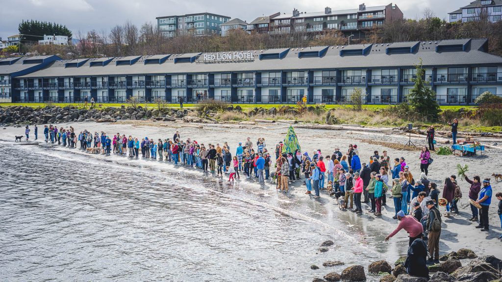 A large group of people standing along the waters edge in Port Angeles, WA